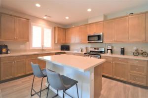 a kitchen with wooden cabinets and a island with bar stools at Oasis at Genesis - 30 Day in Palm Desert