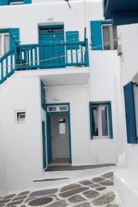 a white building with blue doors and a balcony at Florance Apartments & Rooms in Mikonos