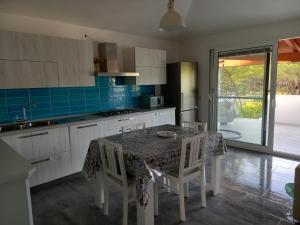 a kitchen with a table and chairs and a kitchen with blue tiles at Casa Maria in Siniscola