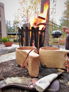 a pair of utensils and a fire in front at Scandinavian Dream Cottages Vikajarvi- Rovaniemi in Vikajärvi