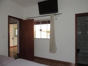 a bedroom with a tv on the wall and a window at Espaço Canastra in Delfinópolis