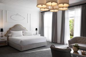 um quarto com uma cama, uma cadeira e um lustre em The Alphen Boutique Hotel & Spa em Cidade do Cabo