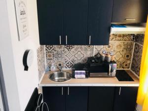 a kitchen with black cabinets and a sink at Le Nid Abbevillois in Abbeville