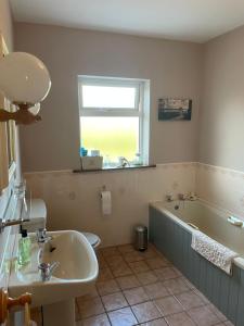 baño con lavabo, bañera y ventana en Rose Cottage en Killarney