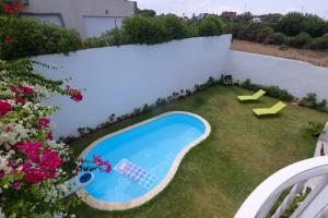 um quintal com piscina e flores em Chez Didier Tamaris Beach em Dar Bouazza