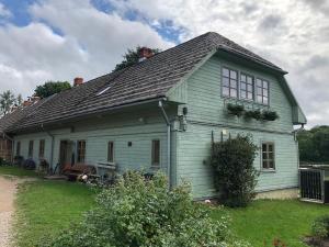 a white house with a black roof at Rumbas in Kuldīga