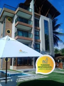 un hôtel avec un parasol en face d'un bâtiment dans l'établissement Pousada Ecos Beach, à Porto de Galinhas