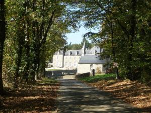 a road leading to a large house with a church at Domaine de Pratulo in Cléden-Poher