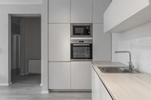 cocina blanca con fregadero y microondas en BLERI Apartment, 2 Bedroom, Free parking, en Pristina