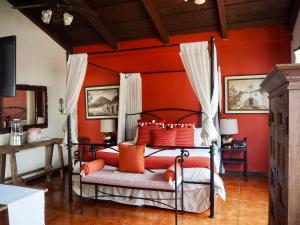 a bedroom with red walls and a bed with orange pillows at Hotel Casa Madeleine B&B & Spa in Antigua Guatemala