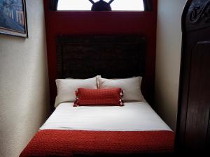 a red and white bed with a red pillow on it at Hotel Casa Madeleine B&B & Spa in Antigua Guatemala