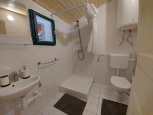 a white bathroom with a toilet and a sink at Apartmaji Hedera in Komen
