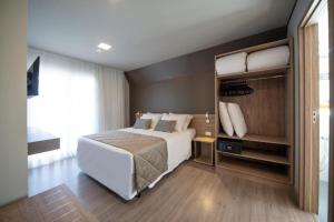 ein Schlafzimmer mit einem großen weißen Bett und einem großen Fenster in der Unterkunft Gramado Resort Apart in Gramado