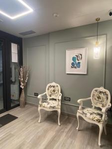 two white chairs sitting in a room with green walls at Hotel Lusitania, Centro Ciudad, Parking Privado in Mérida