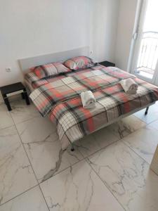 - un lit avec une couverture et des oreillers dans l'établissement XXL APARTAMENT CITY CENTAR 1, à Bitola