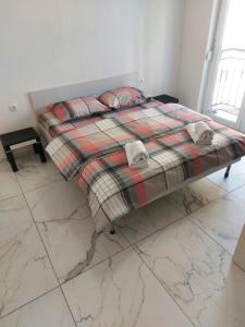 a bed with a blanket and pillows on it at XXL APARTMENTS CiTY CENTAR 1 in Bitola