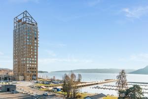 a tall building next to a body of water at MJOS TOWER Apartment - Lovely city view in Ringsaker