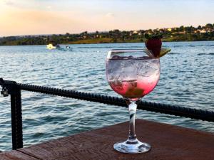 a glass of wine with a strawberry in it next to the water at House Boat "Faroeste Caboclo" in Brasília