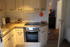 een keuken met witte kasten en een fornuis met oven bij Strandvilla Sophie App 1 in Dierhagen