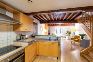a kitchen with wooden cabinets and a living room at Le Saint Jean in Crémieu