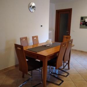 a dining room table with chairs and a clock on the wall at Casa Marta in Cividale del Friuli