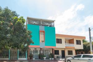 un bâtiment à l'avant bleu avec une voiture garée devant dans l'établissement Hostal Kumbaya, à Santa Marta