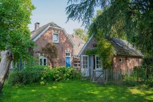 an old brick house with a fence in the yard at Sallandelijk Bakhuis in Olst