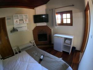 um pequeno quarto com uma cama e uma lareira em Residencial das Araucárias em Gonçalves