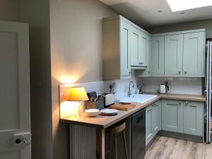 a kitchen with white cabinets and a table with a lamp at Nurse's Cottage in Tomintoul