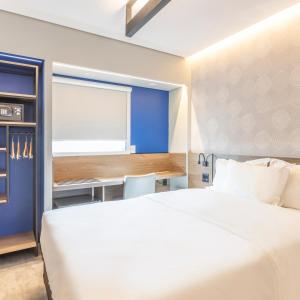um quarto com uma grande cama branca e uma secretária em Tru By Hilton Criciúma em Criciúma