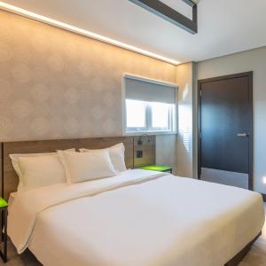 um quarto com uma grande cama branca e uma janela em Tru By Hilton Criciúma em Criciúma