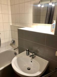 ein Badezimmer mit einem Waschbecken, einem Spiegel und einer Badewanne in der Unterkunft Modernes Apartment Dresden Neustadt in Dresden