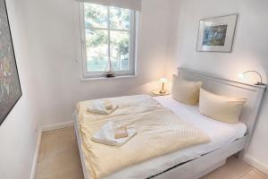 sypialnia z łóżkiem z białą pościelą i oknem w obiekcie Freesenkietz, FW 24 w Zingst