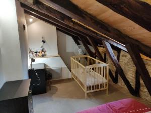 Pokój na poddaszu z łóżeczkiem dziecięcym i drewnianymi sufitami w obiekcie Maison du Bonheur w mieście Saint-Cirgues