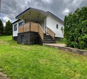 a white house with a porch and stairs in a yard at Chata Thermal House in Kaluža