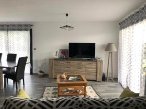 een woonkamer met een tv op een houten dressoir bij Pavillon récent avec 3 chambres in La Brionne