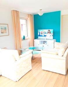 a living room with two white couches and a tv at Seepark - Sonnendeck in Grömitz