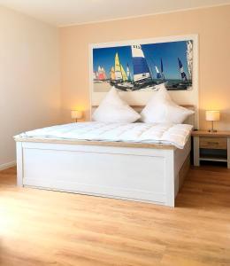 ein weißes Bett in einem Zimmer mit einem Gemälde an der Wand in der Unterkunft Seepark - Sonnendeck in Grömitz