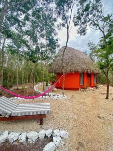 uma cabana vermelha com uma rede em frente em Hotel B. Secreto Maya em Yaxché
