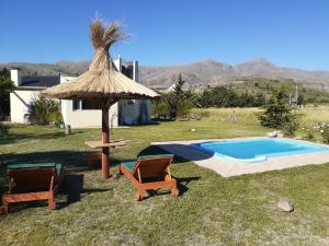 two chairs and an umbrella next to a swimming pool at Lugar Maravilloso in Sierra de la Ventana