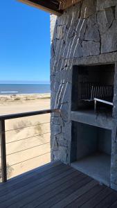 una chimenea de piedra con un banco junto a la playa en Ojos de la Viuda en Punta Del Diablo