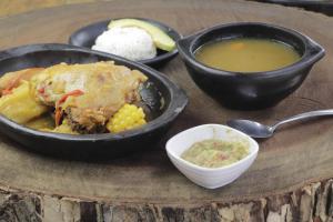 a table with two dishes of food and a bowl of soup at Villa Palmeras Hotel Campestre in Espinal