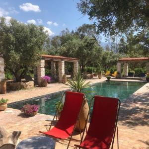 two red chairs sitting next to a swimming pool at Sel d Ailleurs, Atlas Mountain Retreat - adults only in Ouirgane