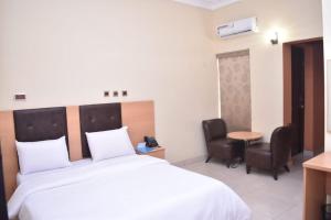 a hotel room with a bed and a table and chairs at AYAAKAJE GUEST HOUSE in Ibadan