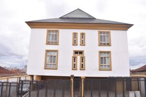 a white house with brown windows behind a fence at AYAAKAJE GUEST HOUSE in Ibadan