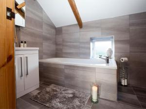 a bathroom with a bath tub and a candle at Deerholme Cottage in Malton