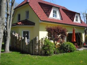 ツィングストにあるAm Deich 01の赤い屋根と木の柵の黄色い家