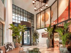 un hall avec des plantes en pot dans un bâtiment dans l'établissement Mondrian London Shoreditch, à Londres