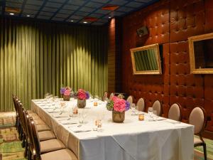 Mondrian London Shoreditch في لندن: طاولة طويلة في غرفة مع الكراسي والورود