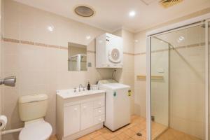 La salle de bains est pourvue de toilettes, d'un lavabo et d'une douche. dans l'établissement 10T Beachfront Apartments, à Lennox Head